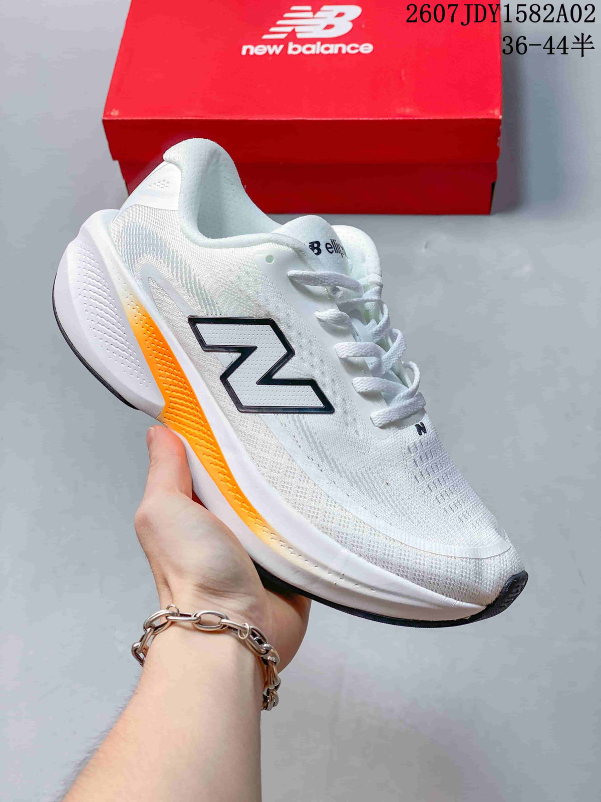 White New Balance running shoe with black detailing and an orange accent on the sole.