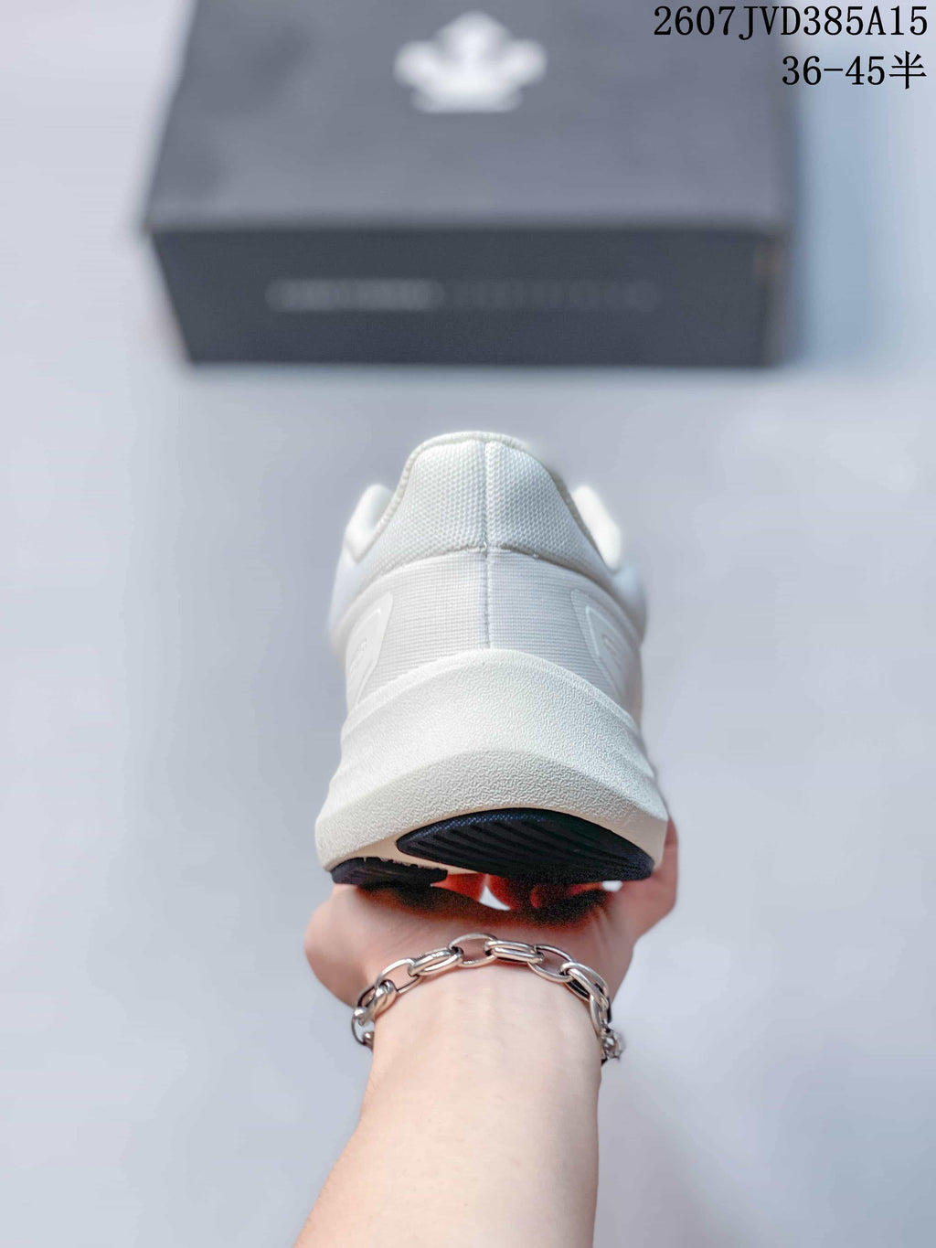 Rear view of the white sneaker showing the padded heel collar, layered heel structure and dark outsole edge.