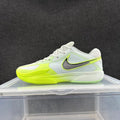 Side view of a low-top Nike basketball shoe in white, light gray, yellow-green and dark gray.