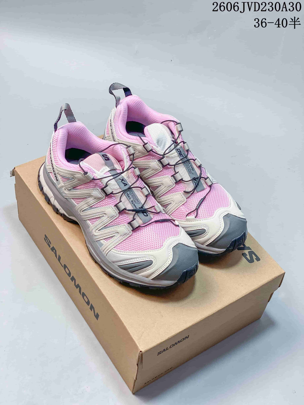 Pair of pink, off-white, and gray Salomon XA Pro 3D trail shoes on a branded box