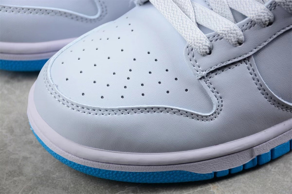 Close-up of the perforated light-colored toe box, gray overlay, white midsole, and blue outsole edge.