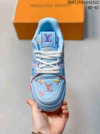 Top view of a light blue sneaker showing white laces, padded tongue, and multicolor patterned detailing.