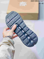 Close-up of the patterned outsole on a dark gray sneaker, showing segmented tread sections and open cushioning cavities.