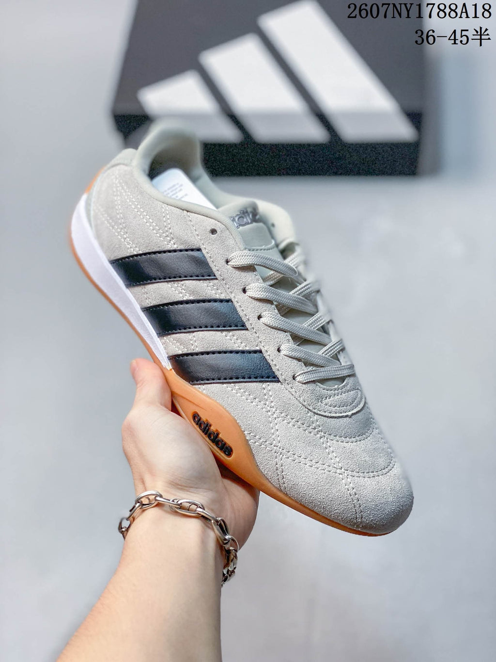 Angled side view highlighting the light upper, dark three-stripe detailing, laces and gum outsole.