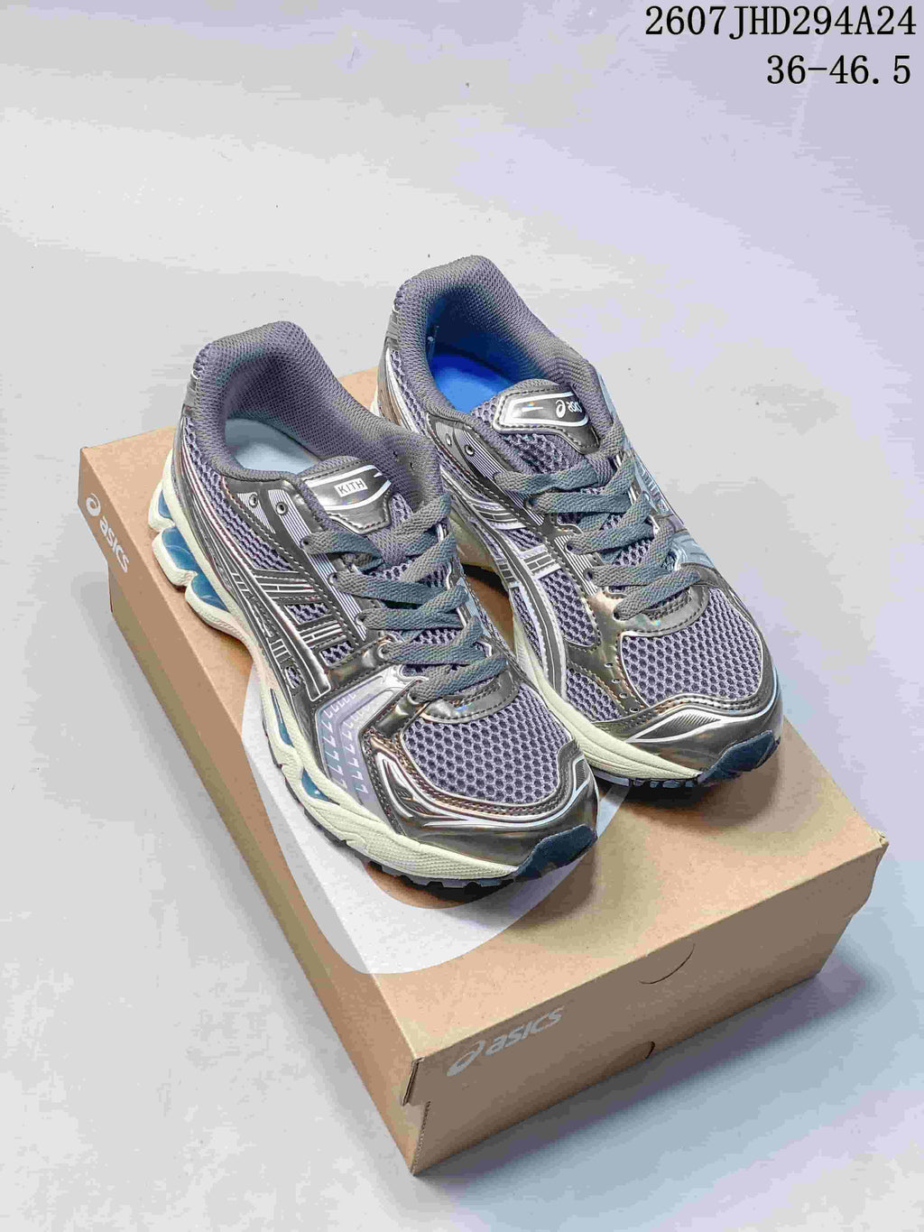 Pair of silver-gray ASICS Gel-Kayano 14 sneakers with blue accents displayed on a shoebox; image text shows style code 2607JHD294A24 and size range 36–46.5.