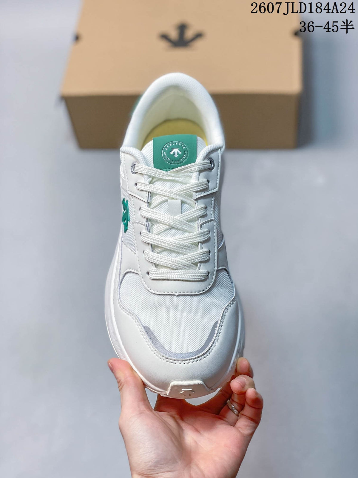 Front view of the white sneaker showing white laces, mesh-like toe panel, green tongue detail, and rounded toe.