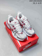 Pair of white, silver and red Nike V2K Run sneakers displayed on a red Nike shoebox.