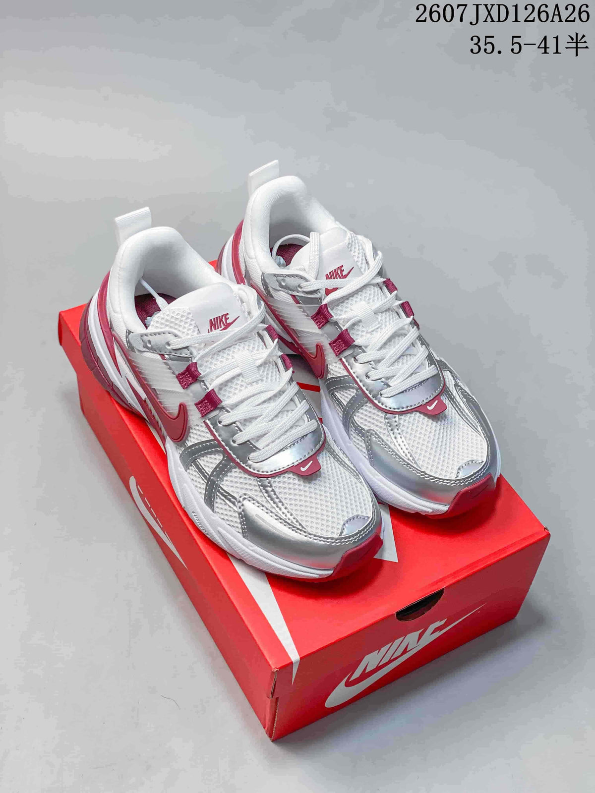 Pair of white, silver and red Nike V2K Run sneakers displayed on a red Nike shoebox.