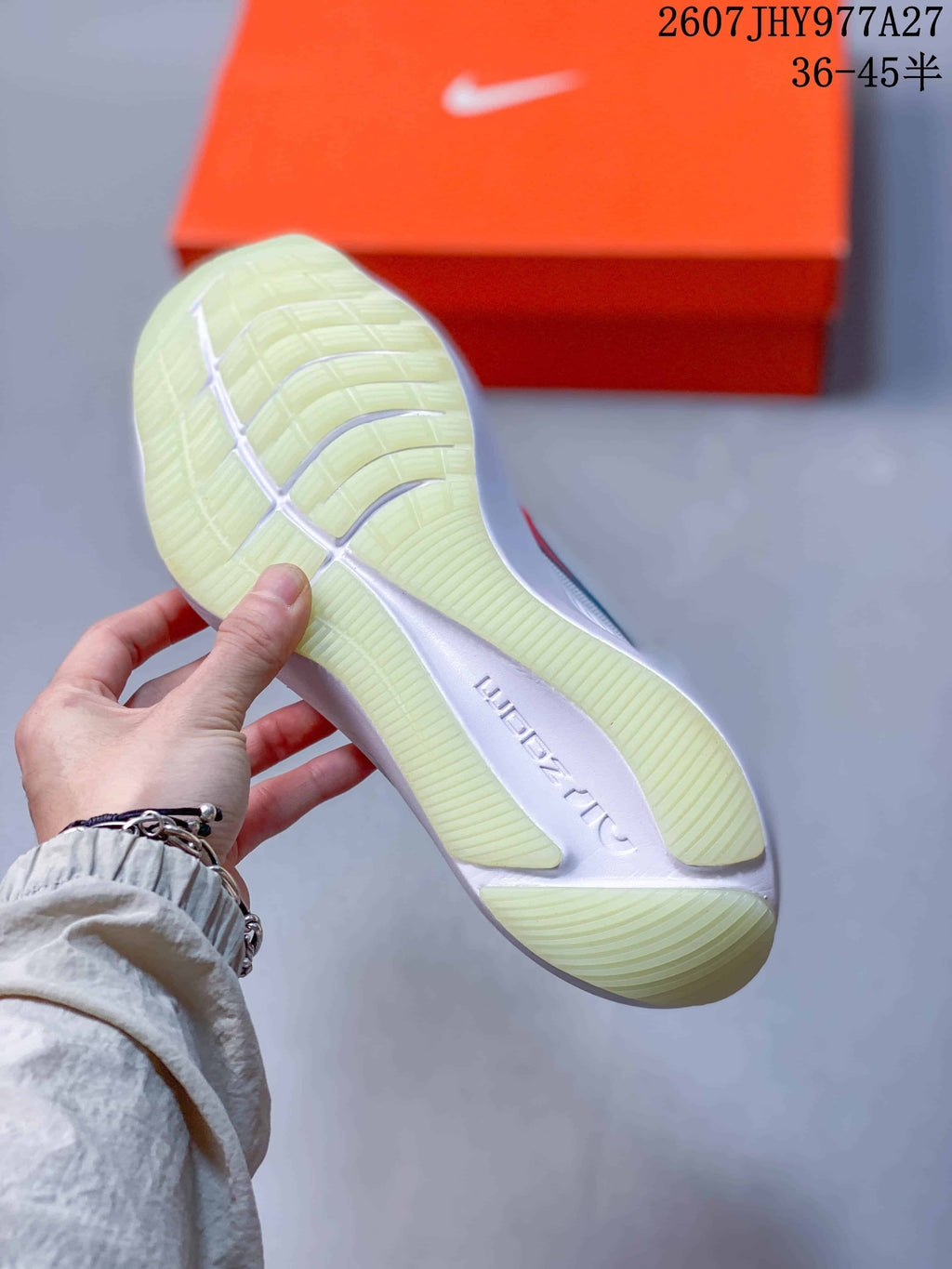 Close-up of the translucent outsole and ribbed tread pattern on a white running shoe.
