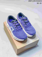 Pair of purple On Cloudmonster 3 running shoes displayed on a shoebox, showing the white sculpted midsoles and purple laces.