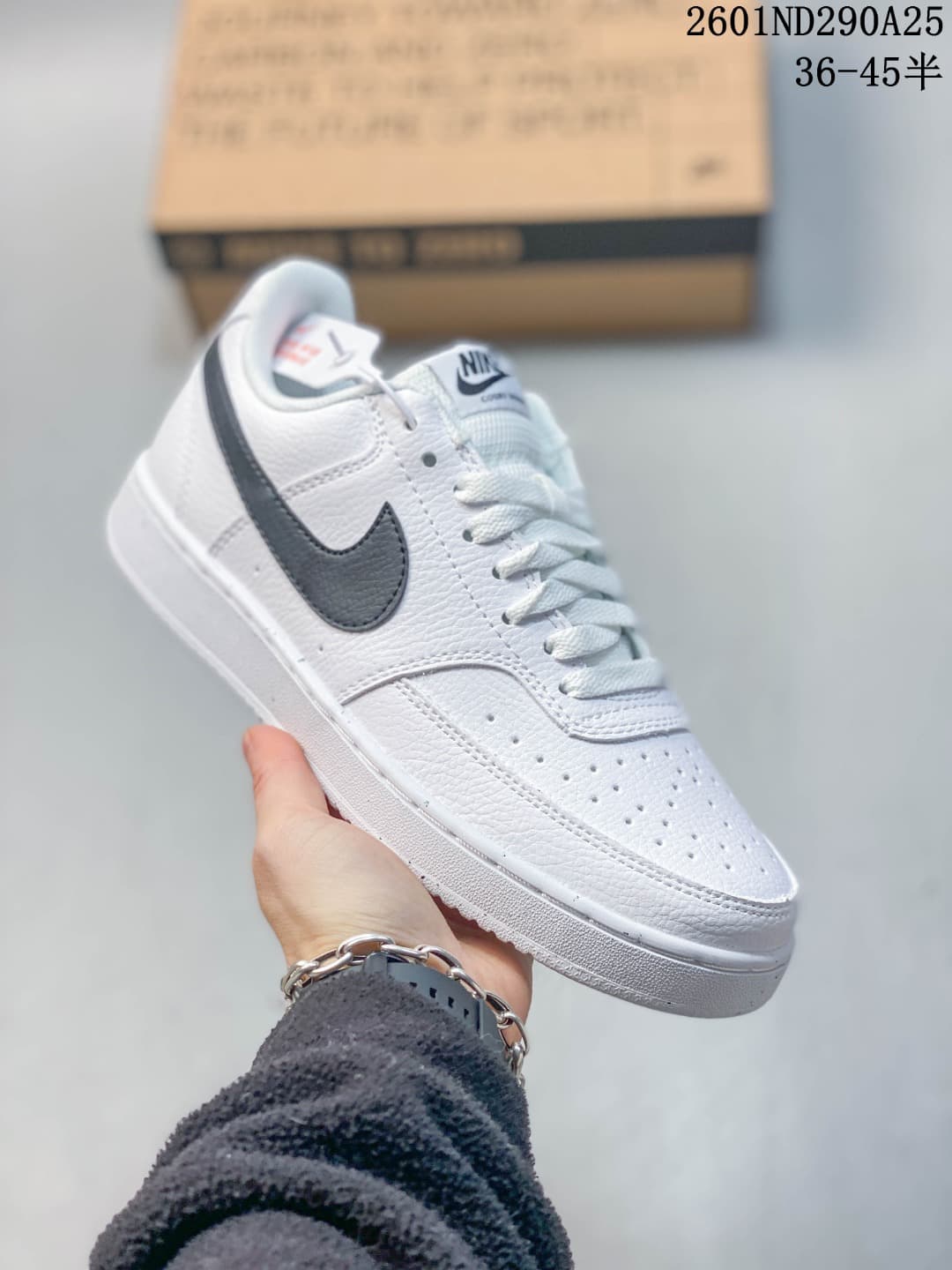 Angled side view of the white sneaker showing black Swoosh detailing, perforated panels, laces, and the rubber outsole.