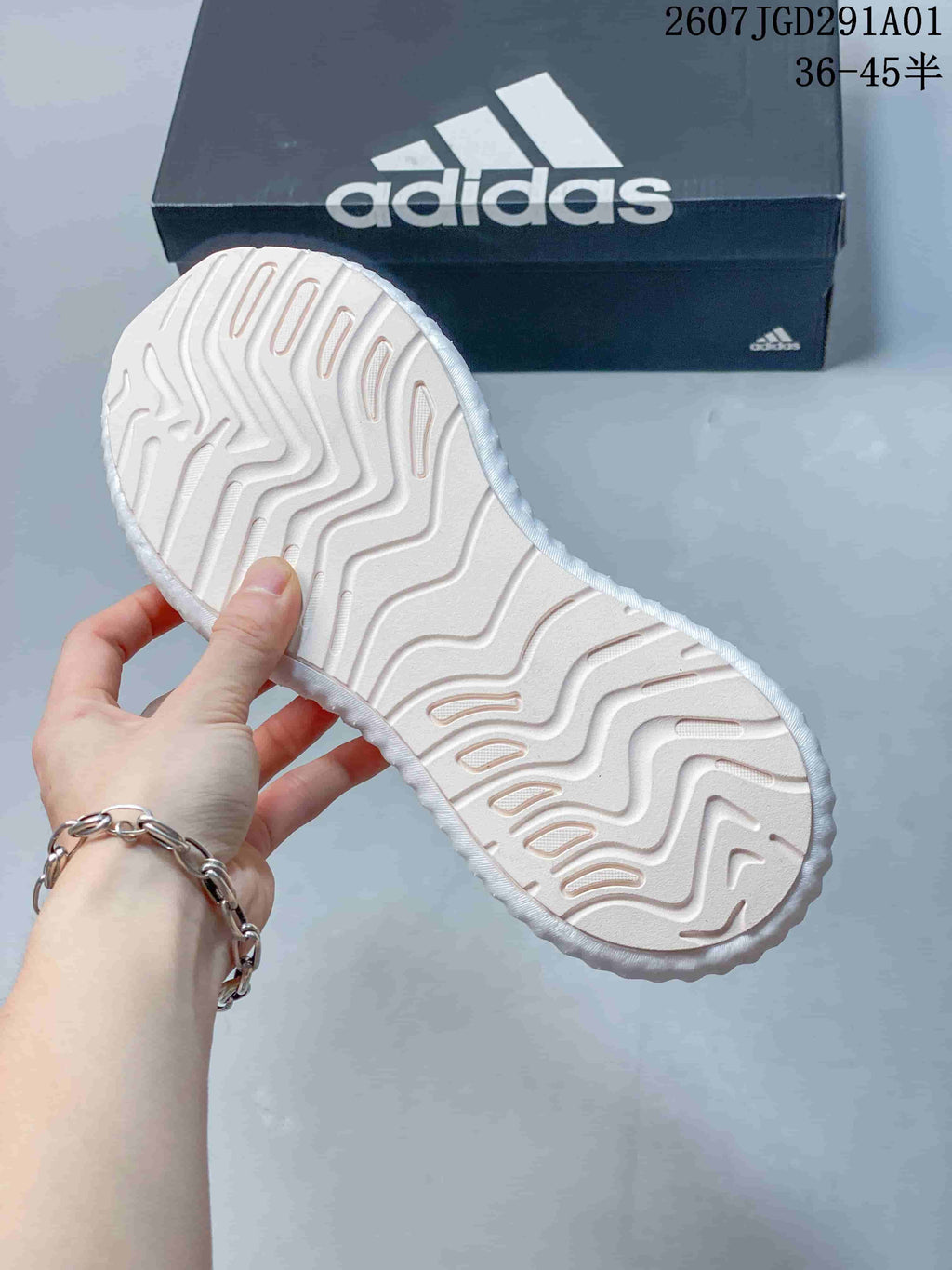 Close-up of the textured outsole on the white and pale pink sneakers
