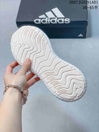 Close-up of the textured outsole on the white and pale pink sneakers