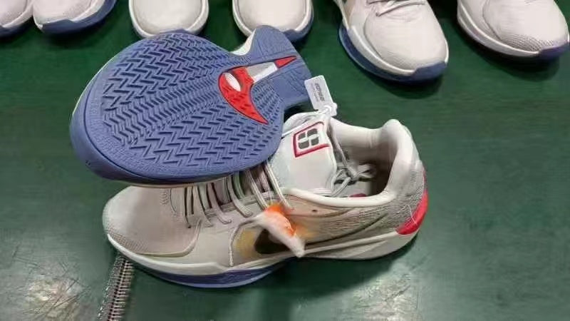 Gray low-top basketball shoes with a blue patterned outsole and red accents.