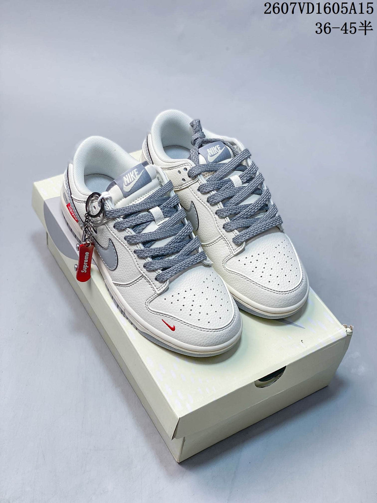 Pair of white and gray Nike low-top sneakers with red accents displayed on a shoebox.