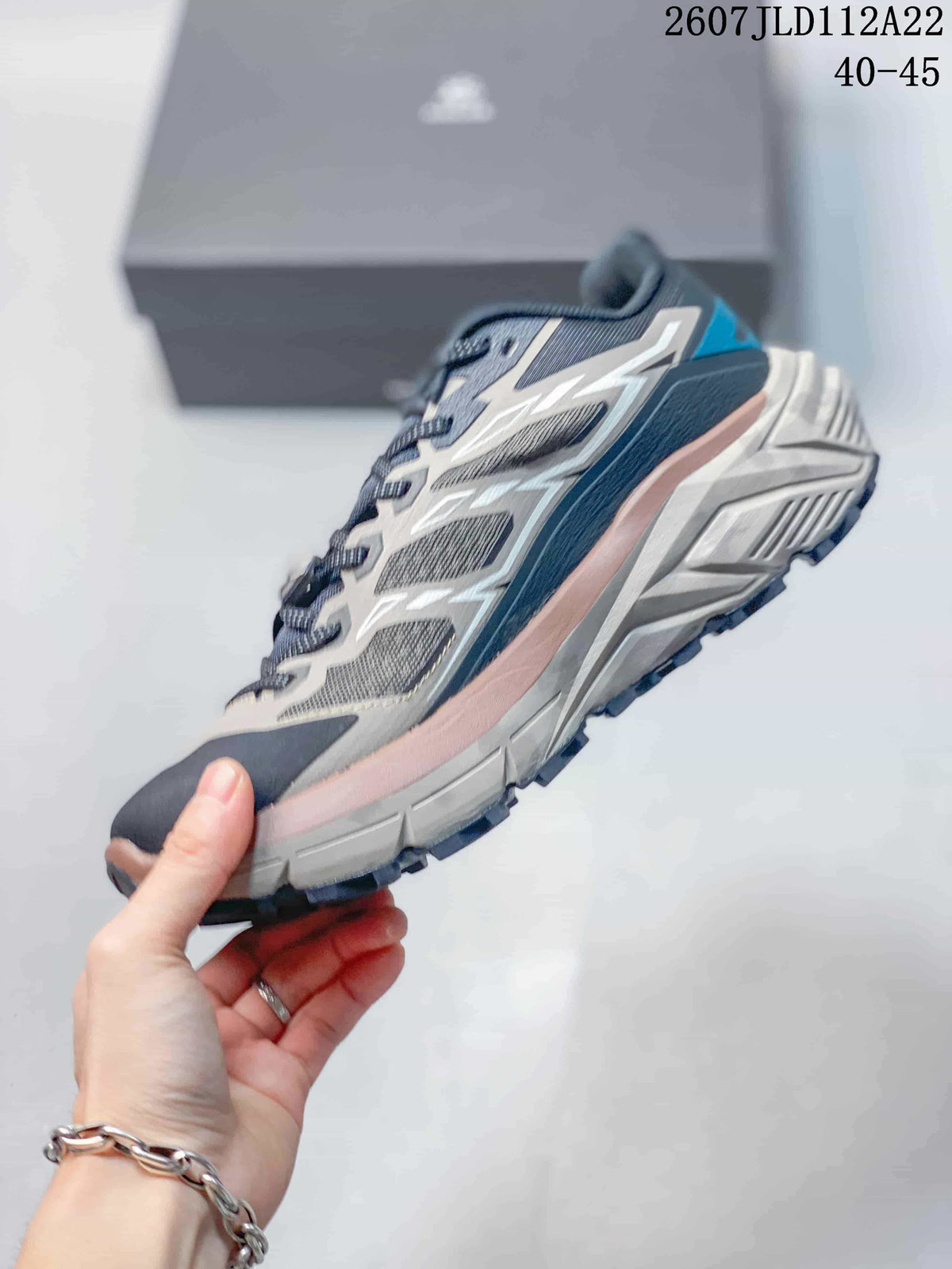 Side profile of the low-top trail shoe showing mesh panels, white overlays, pink midsole detailing, and a textured outsole.
