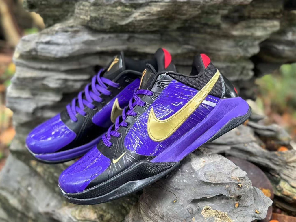 Angled view of both purple and black Nike Kobe 5 shoes with gold-colored logos and purple laces.