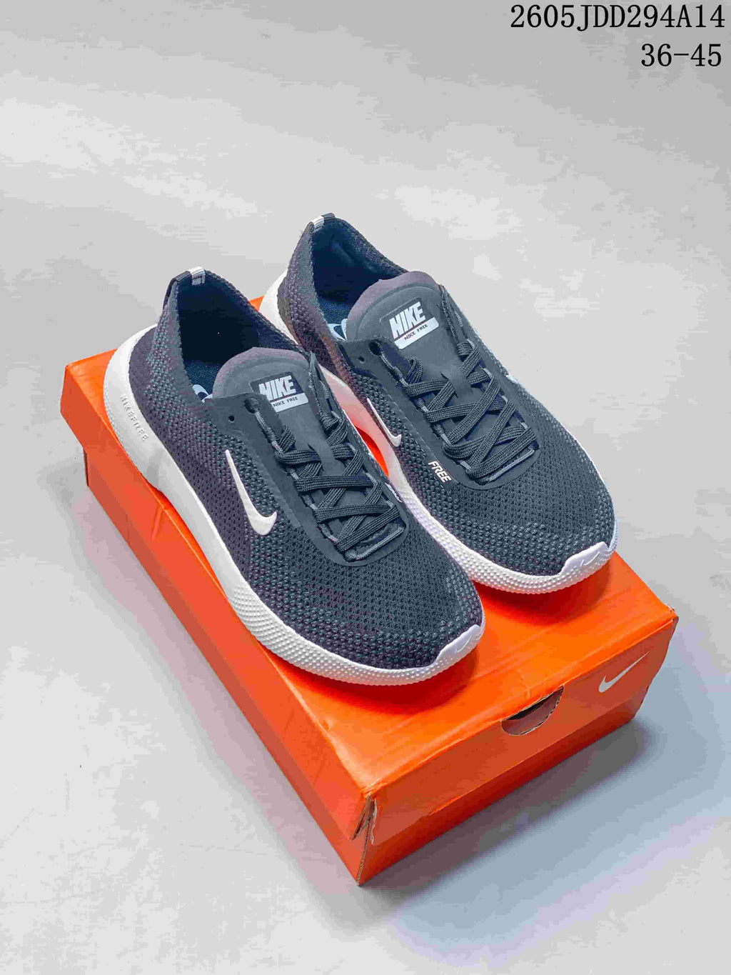 Pair of dark gray Nike Free sneakers with white soles displayed on an orange Nike shoebox; overlay shows style code 2605JDD294A14 and size range 36–45.