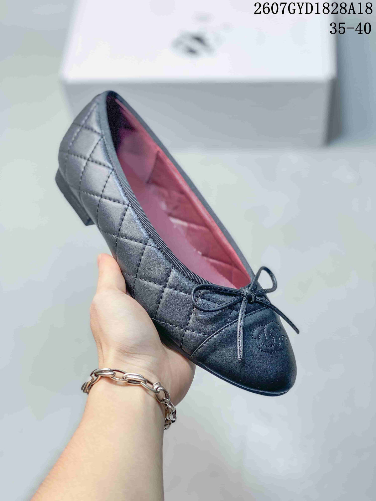 Angled view of a black quilted ballet flat with bow detail and visible Chanel branding.