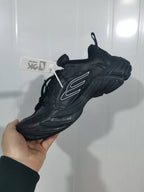 Angled view of the black sneaker showing the side detailing, laces, pull tab, and sculpted sole.