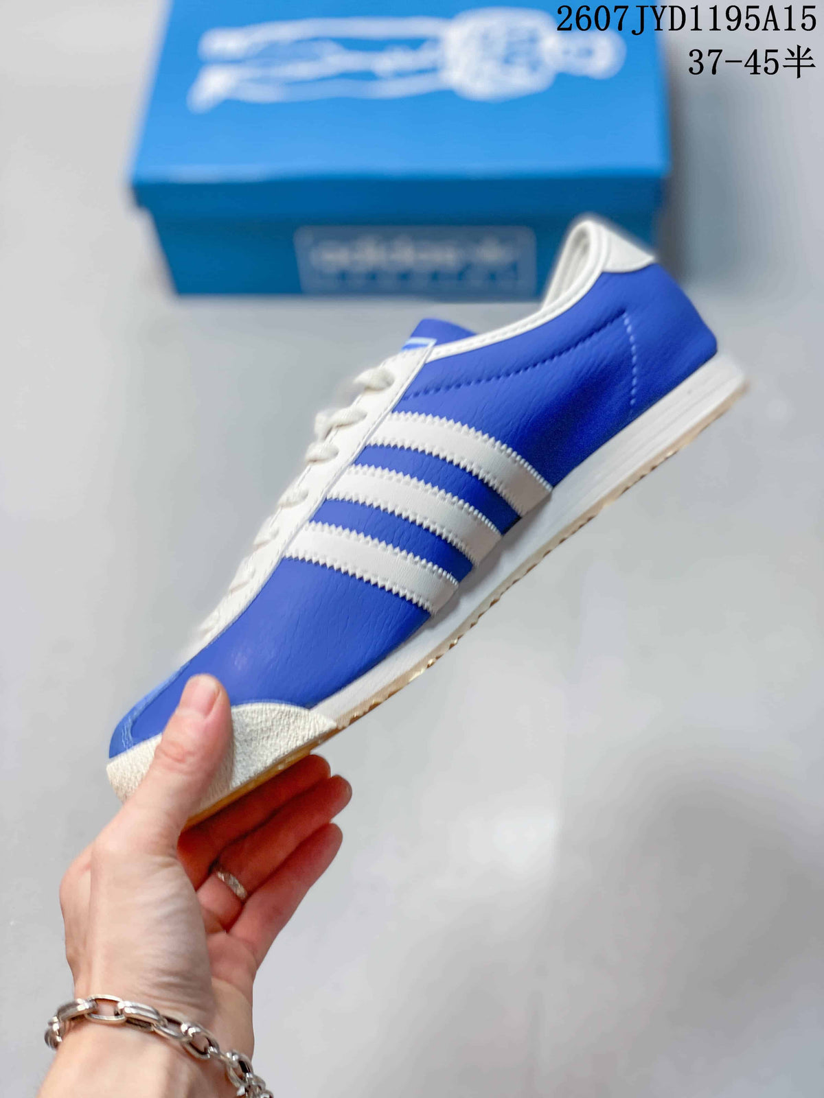 Side view of the blue sneaker showing cream three-stripe overlays, white midsole and gum outsole.