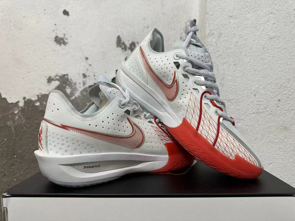 Angled view of white Nike sneakers with red accents and patterned overlays