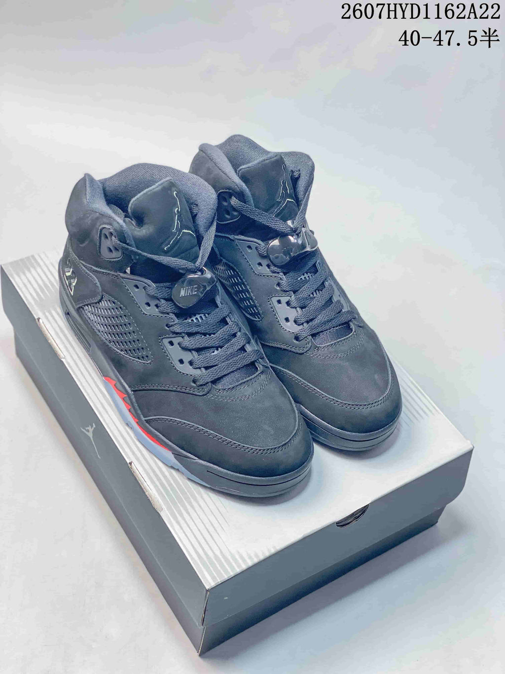 Pair of black Nike Air Jordan 5 Retro high-top sneakers displayed on a shoebox, with red accents and translucent outsole sections; image text shows style code 2607HYD1162A22 and size range 40–47.5.