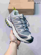 Three-quarter side view of the Salomon XA PRO 3D Seasonal sneaker showing the gray and white upper, dark outsole and neon yellow accents.