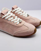 Close-up of the sneaker toe, white laces, stitched panels, and decorative lace charm.