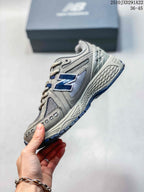 Side view of a grey and silver sneaker with navy side logo and layered panels