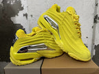 Yellow sneakers shown from the side, highlighting the sculpted panels and silver-tone accents.