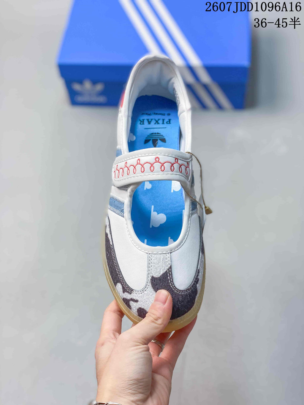 Top view showing the hook-and-loop strap, blue printed insole, patterned toe panels, and white upper.