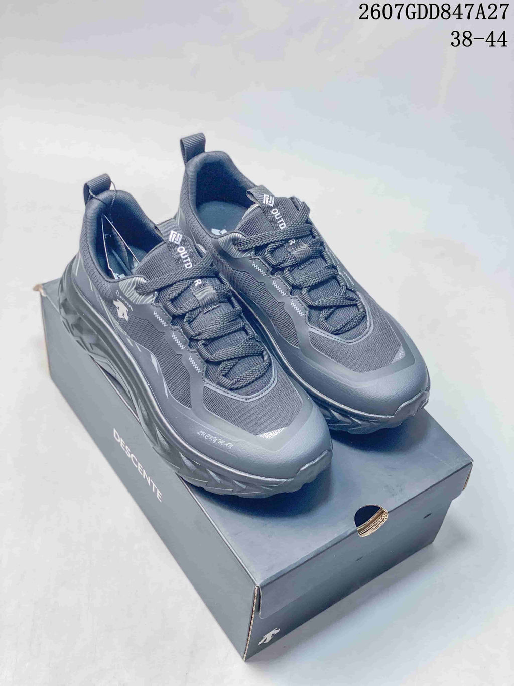 Pair of black DESCENTE TERRAIND low-top sneakers displayed on a branded shoebox.