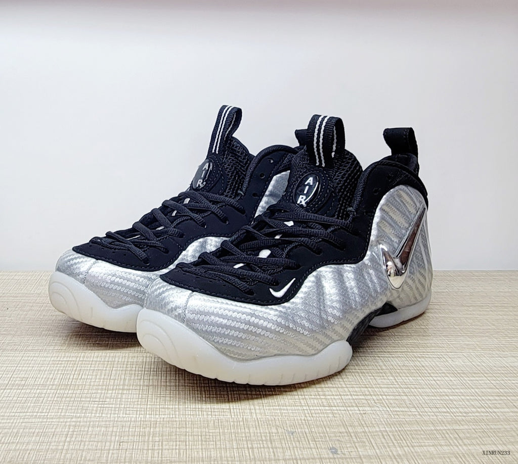 Front three-quarter view of silver Nike Foamposite Pro shoes with black laces