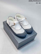 White Mary Jane flats with dark trim and buckle straps, photographed as a pair.