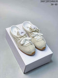 Pair of cream Alo mule sneakers displayed on a white box, showing the laces, branding, and gum-colored outsoles.