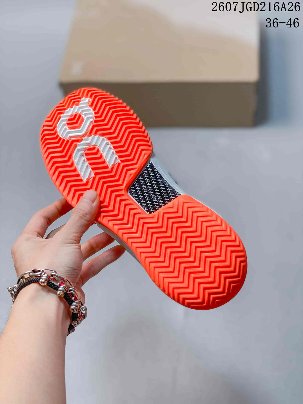 Close view of the bright orange outsole showing a repeating herringbone-style tread and central textured insert.
