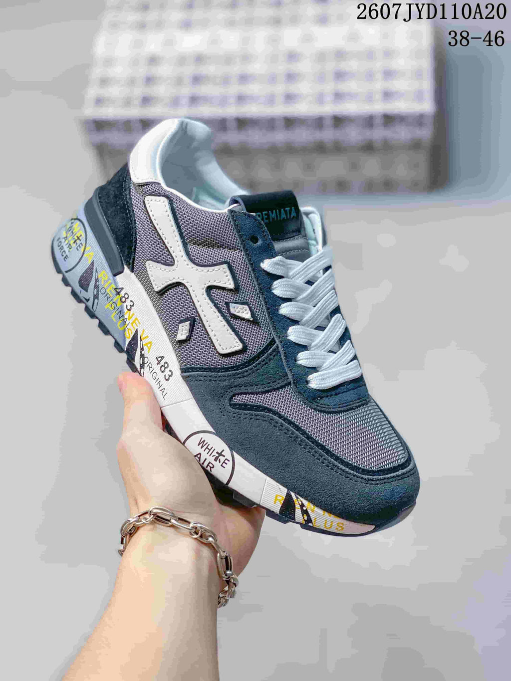 Angled side view of the Premiata sneaker showing the white side emblem, gray mesh panels, navy overlays, and graphic midsole.