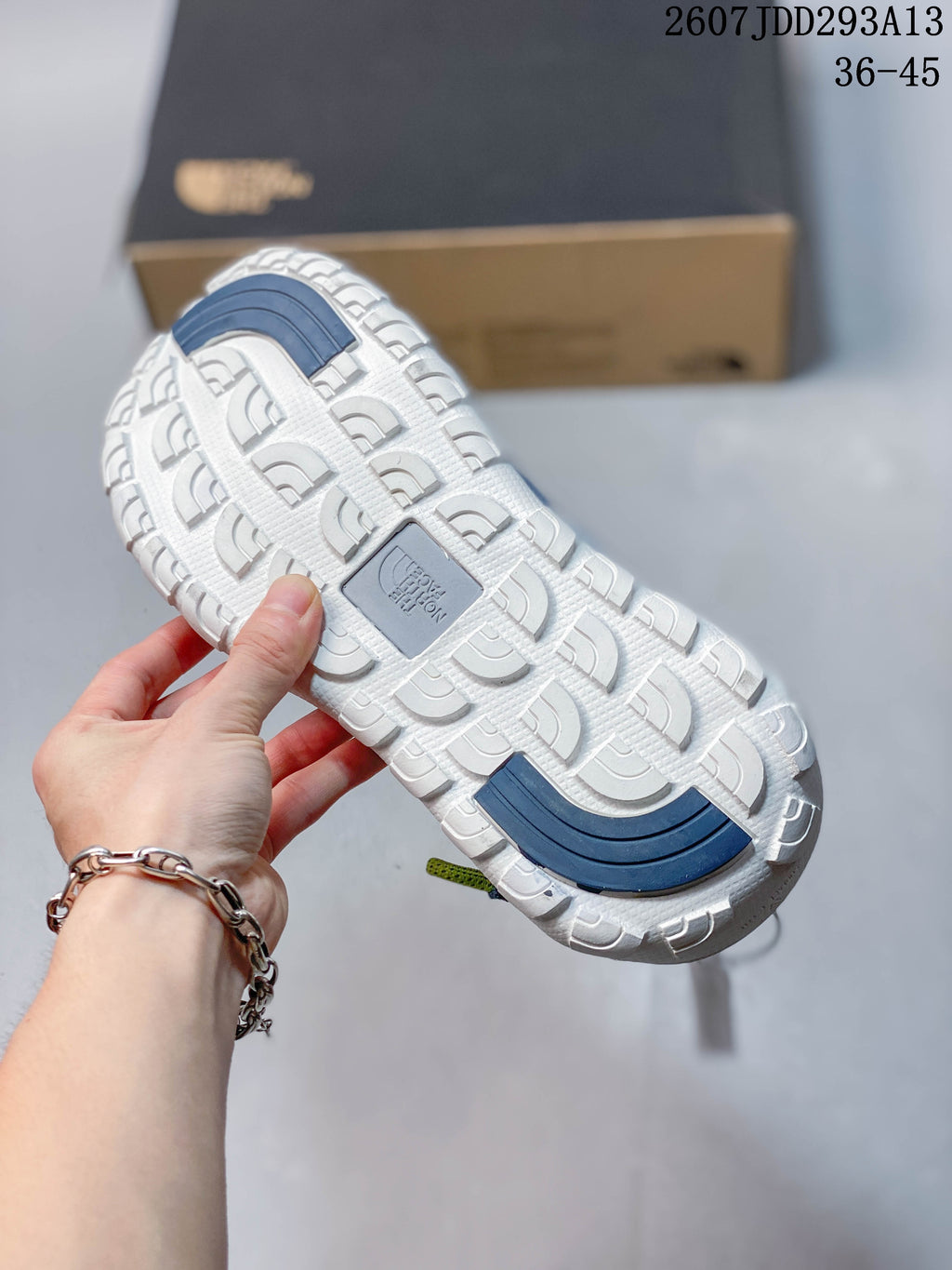 Underside view showing the sandals’ light-colored textured tread and contrasting blue outsole sections.