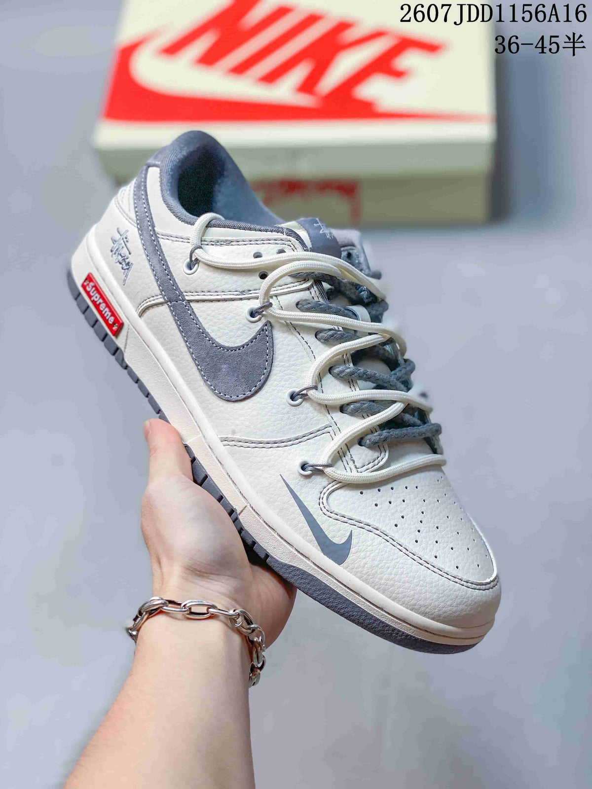 Angled side view of an off-white and gray Nike SB Dunk Low sneaker with branded side details and a gray outsole; image text shows style code 2607JDD1156A16 and size range 36–45.5.
