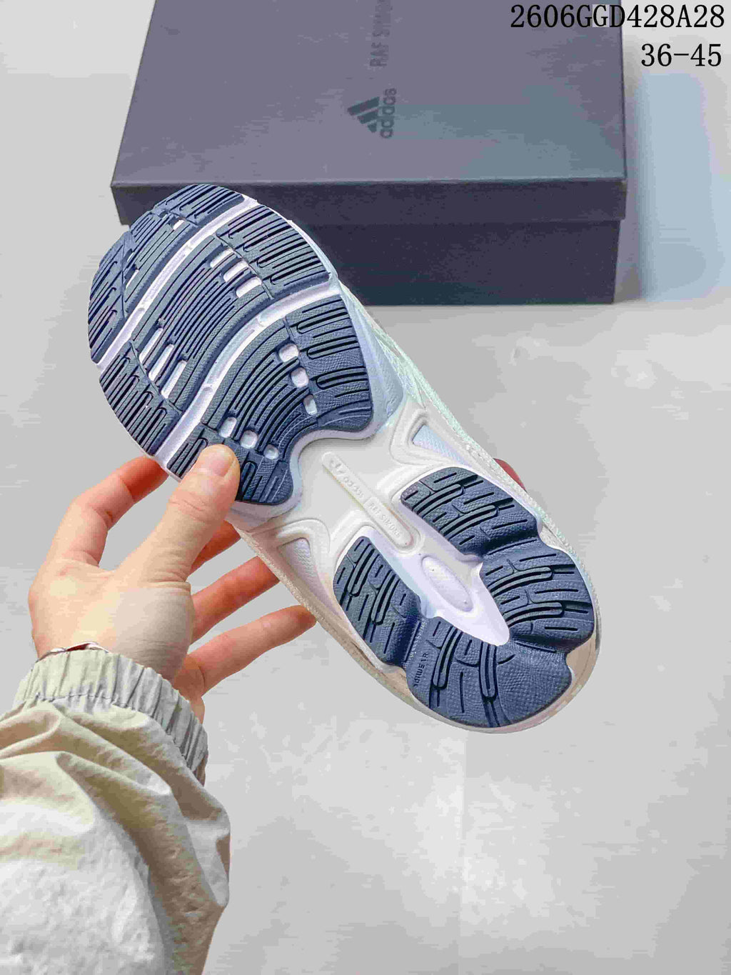 Underside of a white sneaker showing a navy segmented outsole