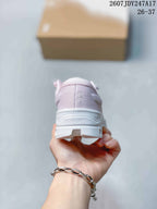 Rear view of the pale pink shoe showing the padded collar, On branding, and heel marked Helion.