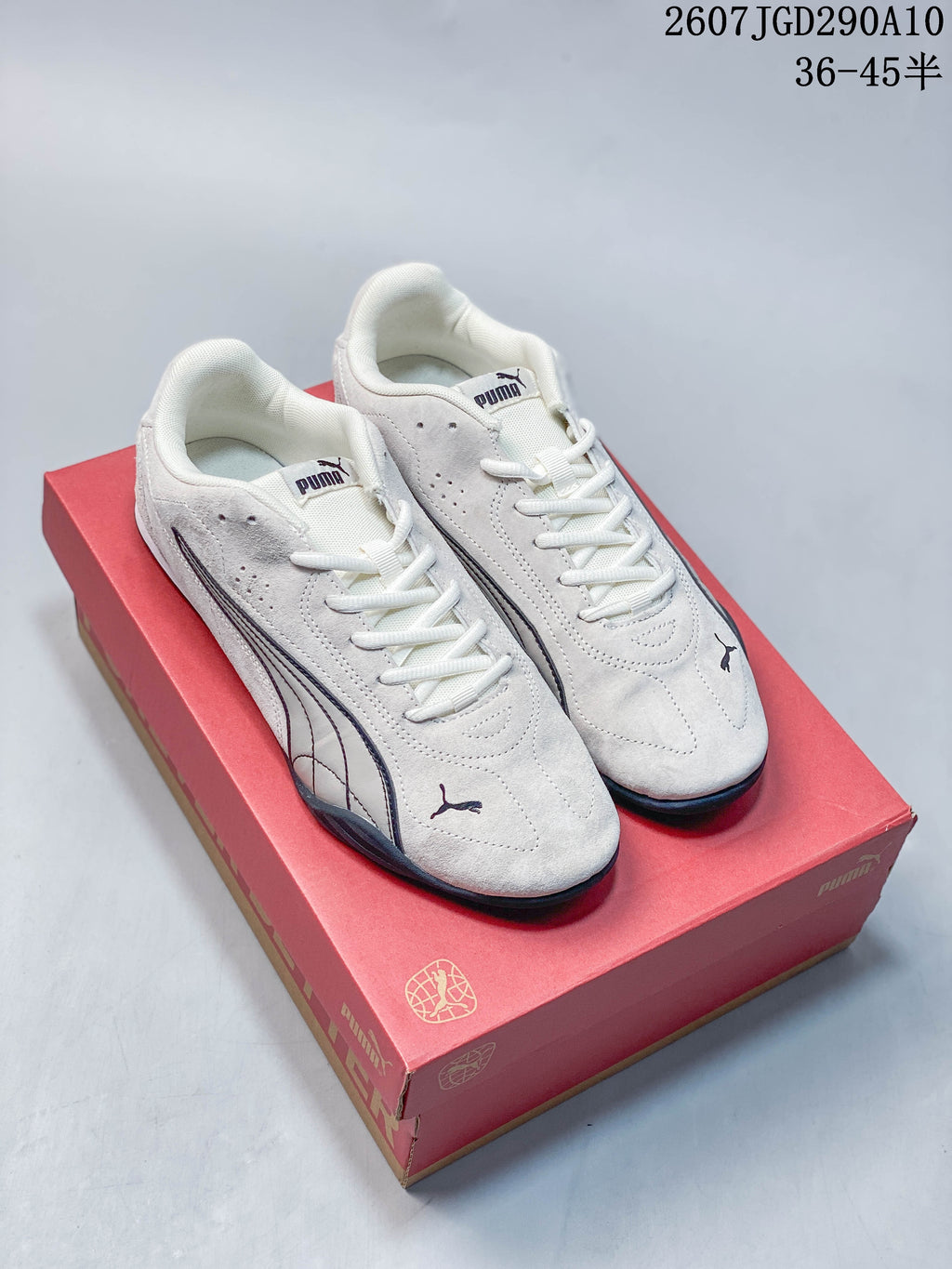 Pair of white Puma low-top sneakers displayed on a red Puma shoebox.