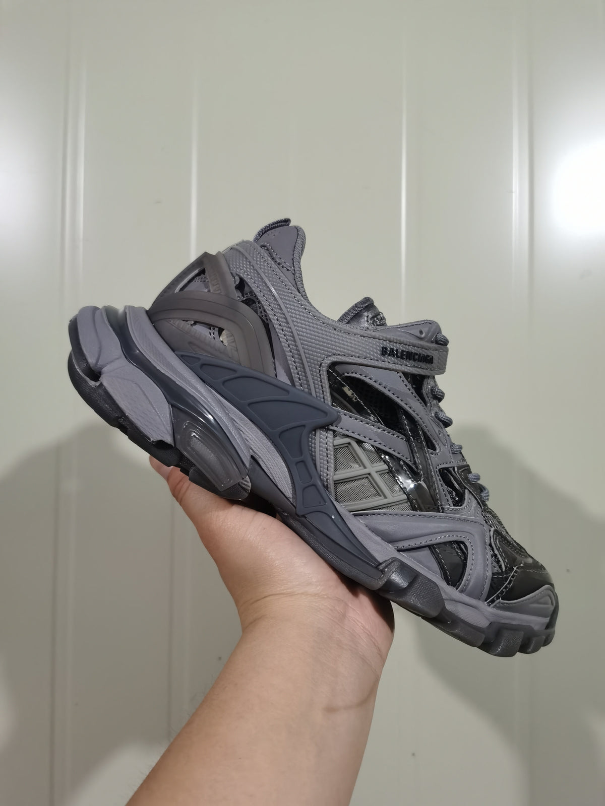 Side view of the dark grey Balenciaga sneaker showing layered panels, reflective accents and the chunky outsole.