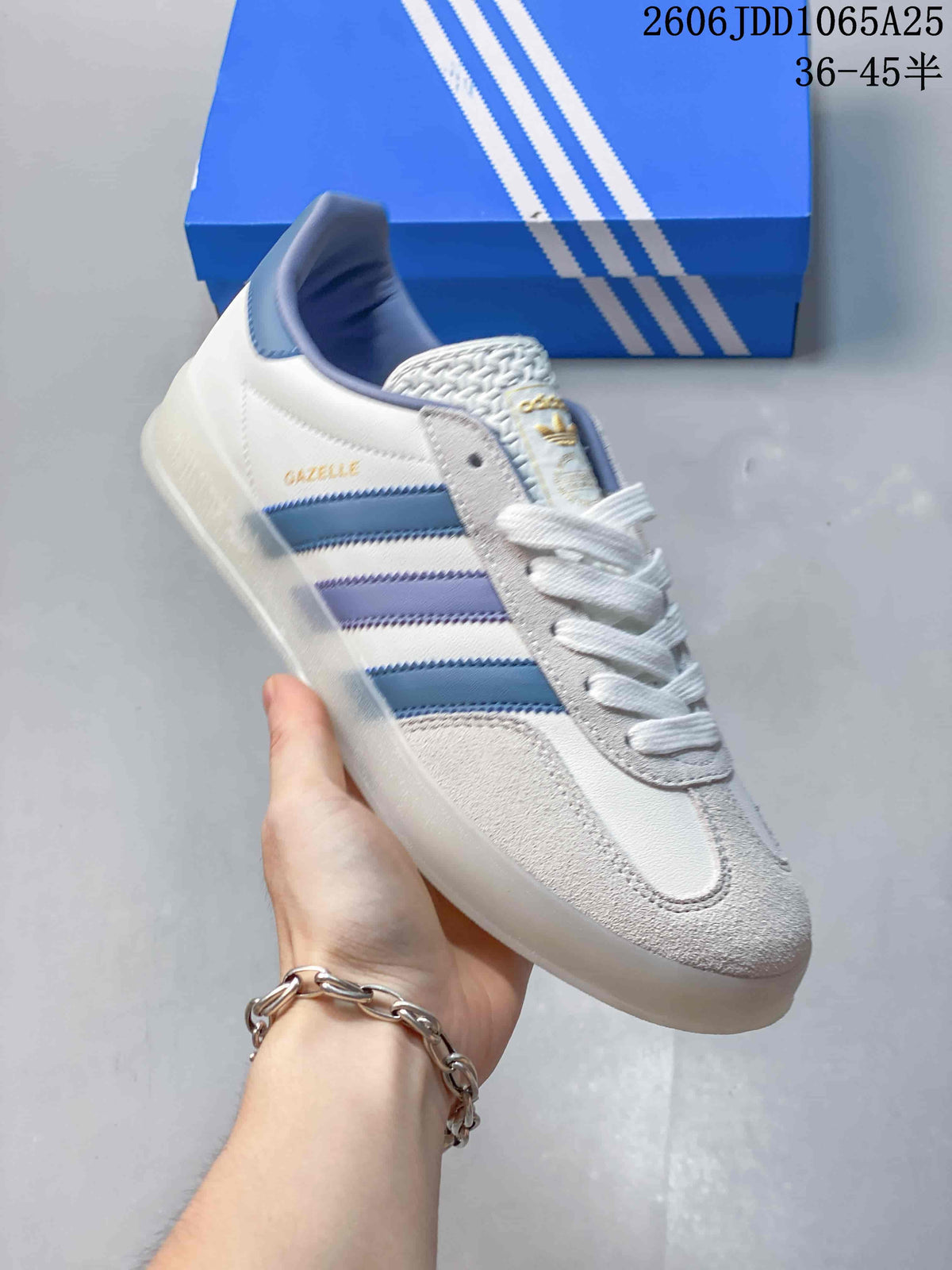 Angled side view showing the Gazelle branding, white upper, blue and lavender stripes, and translucent outsole.