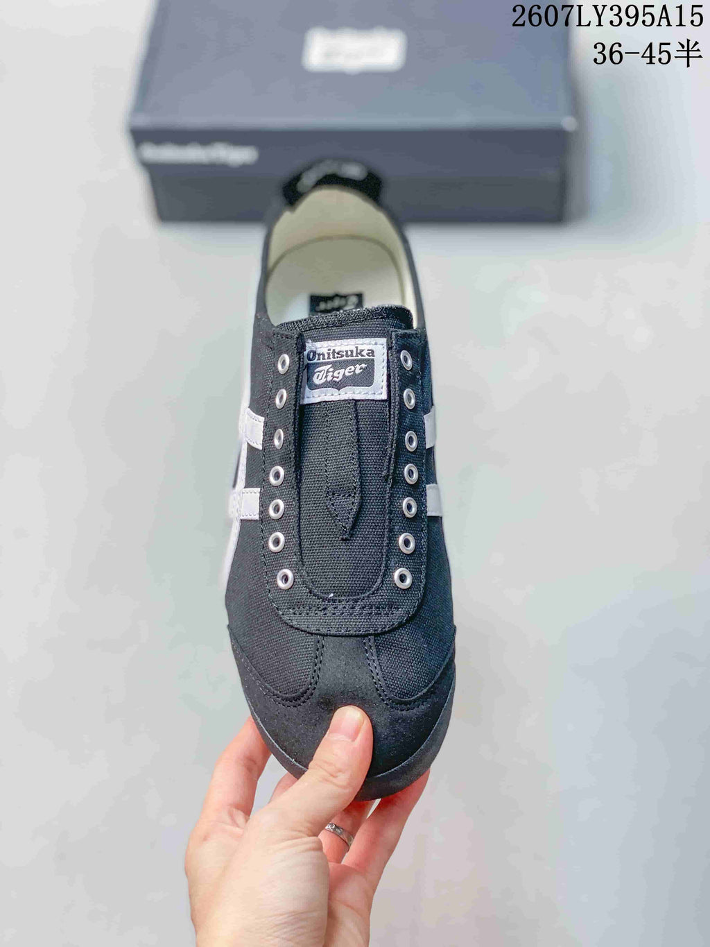 Top view of the black sneaker showing the tongue branding, metal eyelets, stitched toe panels, and light-colored lining.