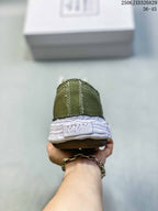 Rear view of an olive sneaker showing the stitched heel panel, MMY heel branding, white midsole, and brown outsole.