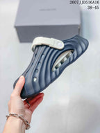 Side view of a navy covered-toe sandal showing the perforated upper, textured surface, and white adjustable strap.