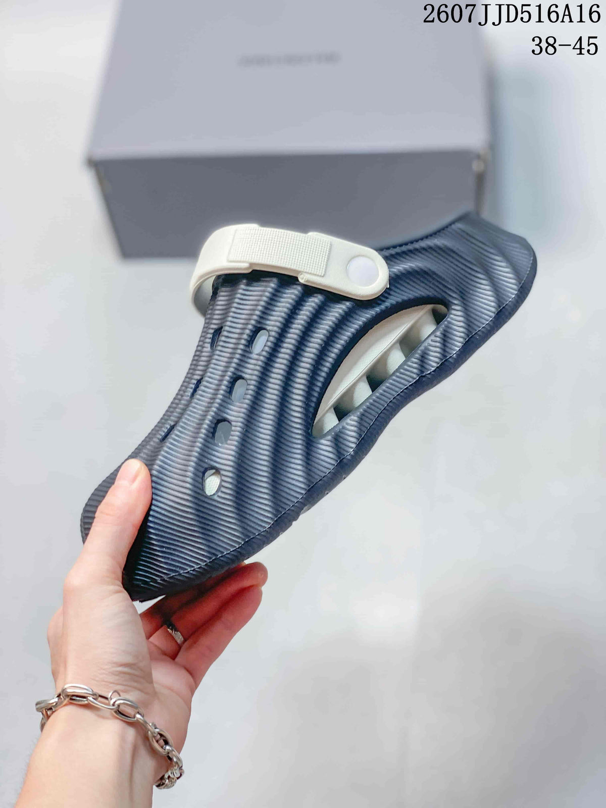 Side view of a navy covered-toe sandal showing the perforated upper, textured surface, and white adjustable strap.