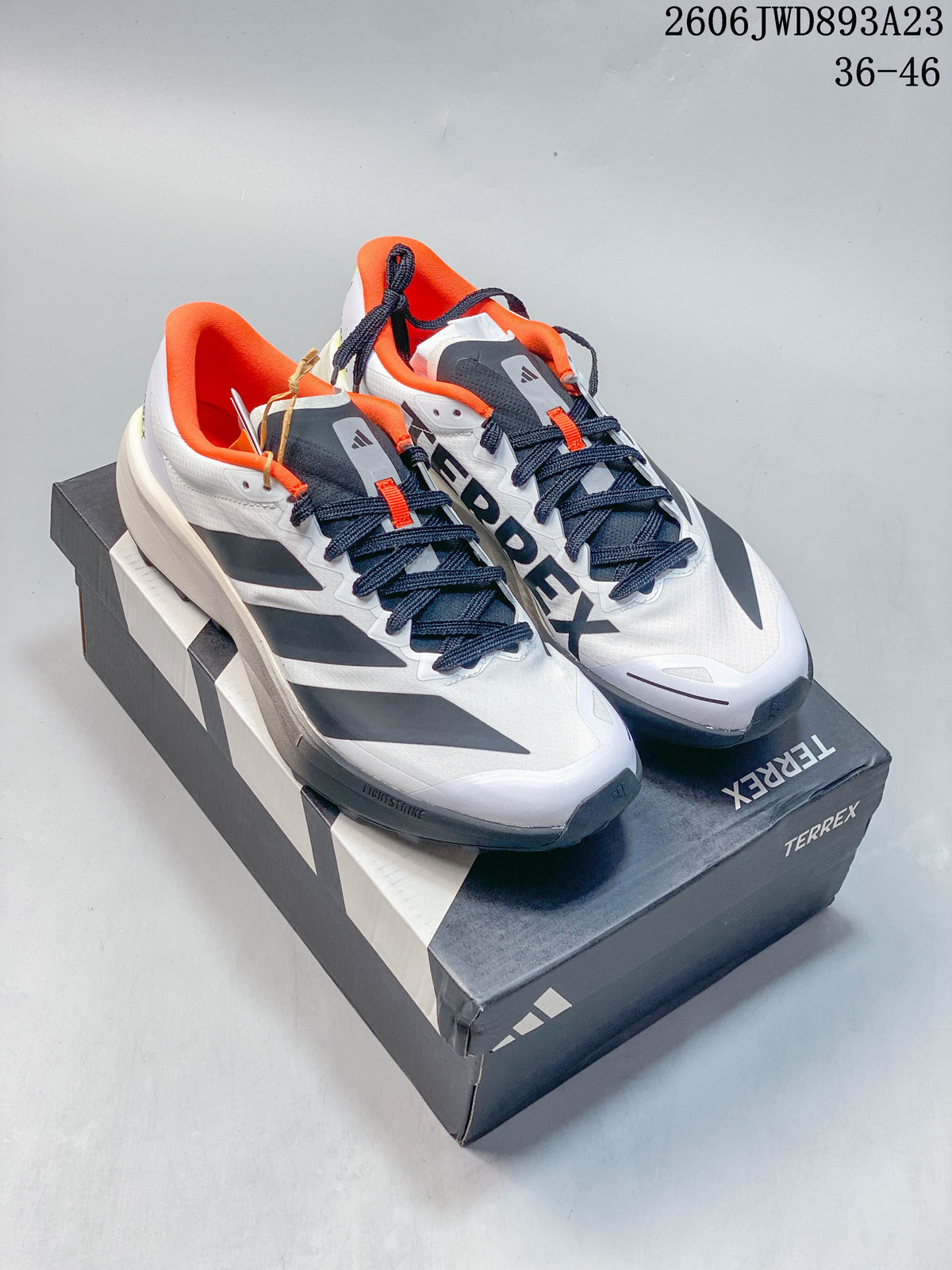 Pair of white adidas Terrex Agravic 4 trail running shoes with dark gray, orange, and neon yellow details.